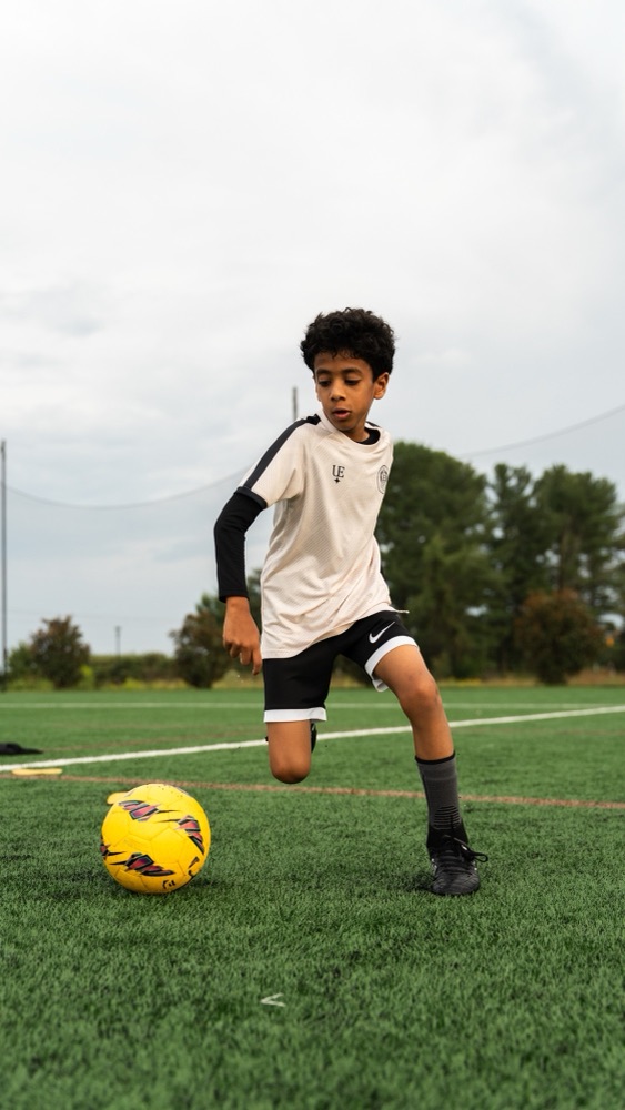 A player controlling a yellow ball during a drill